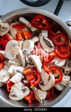 Primo piano di funghi tritati e peperoni colorati saltati in una teglia calda Foto Stock