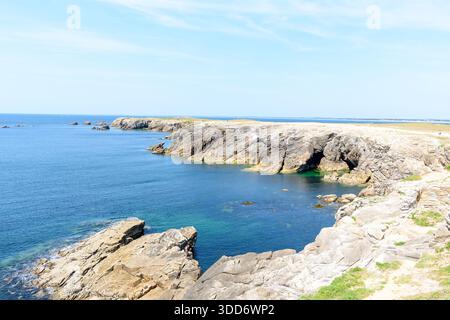 Le scogliere rocciose sbiancate dal sole fanno da cornice a una tranquilla insenatura turchese a Pointe Beg-an-AUD a Saint Pierre Quiberon, con acque cristalline e un cielo aperto luminoso che crea una serena atmosfera costiera. Foto Stock