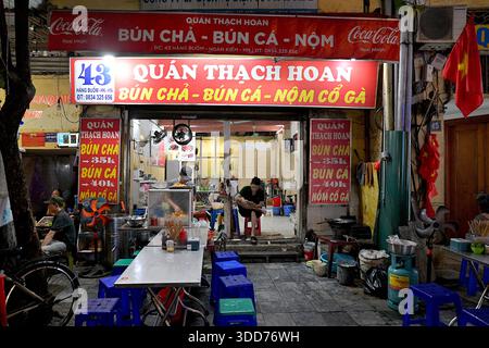 Un ristorante nel quartiere Vecchio che vende Bun Cha, un piatto vietnamita di maiale alla griglia e spaghetti di riso bianco, con posti a sedere all'aperto su sgabelli bassi di plastica Foto Stock