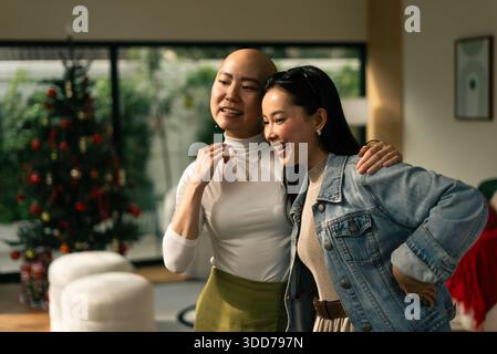 Amiche asiatiche che abbracciano, ridono, condividono la felicità a casa per le vacanze Foto Stock
