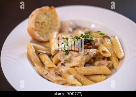 Penne con salsa al tartufo con pancetta e pane all'aglio. Foto Stock