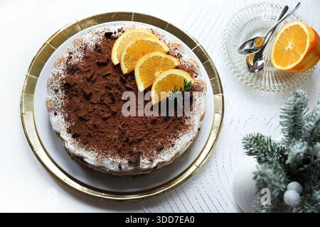 Tiramisù. Torta tiramisù al cioccolato e all'arancia, spolverata con cacao e pezzi di cioccolato, decorata con fette d'arancia. Decorazione natalizia. Foto Stock