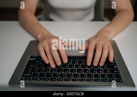 Colpo ritagliato di mani femminili che digitano sulla tastiera del notebook, lavorano in remoto da casa, connettendosi online, elaborando dati, codificando, gestendo le attività aziendali Foto Stock