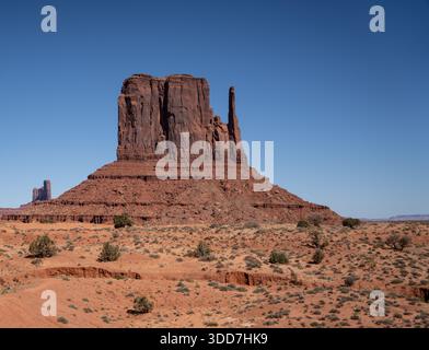 West Mitten Butte si erge in un vasto e arido deserto della Monument Valley sotto il cielo azzurro Foto Stock
