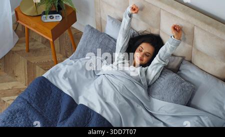 Vista dall'alto Caucasico sorridente donna felice svegliarsi al mattino sdraiato nel letto di casa camera da letto ragazza sorriso svegliarsi svegliarsi dopo aver dormito sano Foto Stock