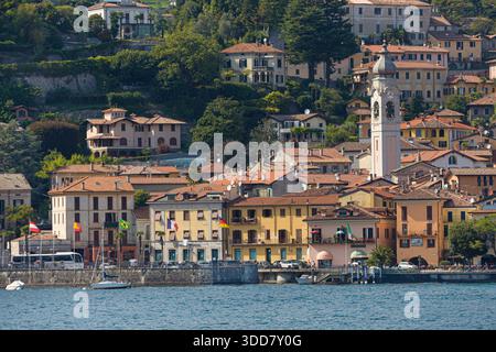 Menaggio, Italia - 21 agosto 2021: Veduta del villaggio di Menaggio visto dal lago di Como con edifici tradizionali e la chiesa che si erge sopra il c Foto Stock