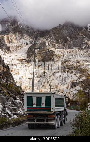 Un grande dumper verde e bianco percorre una strada tortuosa all'interno della cava di marmo di Carrara in Toscana, Italia Foto Stock