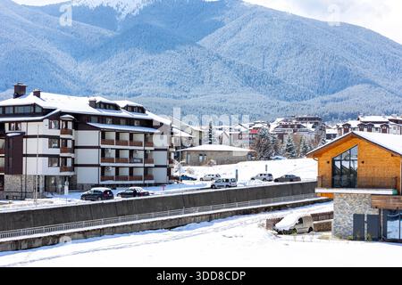 Bansko, Bulgaria - 9 aprile 2025: Fiume Glazne nella città bulgara, case alberghiere e cime innevate dei monti Pirin Foto Stock