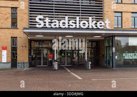 Ingresso allo Stadsloket (sportello della città) di Amsterdam. Edificio degli uffici governativi municipali con grande segnaletica e porte scorrevoli in vetro. Foto Stock