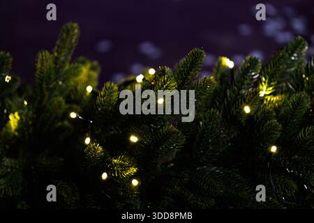 Albero di Natale artificiale ecologico con luci calde. Albero di Natale artificiale realizzato con materiali riciclati, decorato con calde luci a corda, di Foto Stock