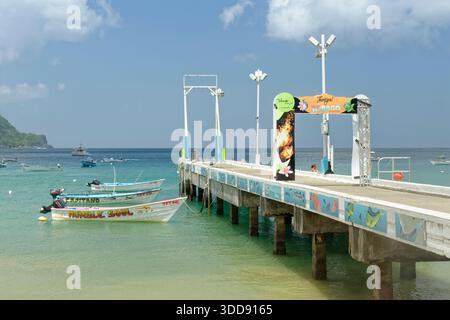 Molo/molo di Charlotteville e molte barche da pesca ormeggiate colorate, Man-o-War Bay, sulla costa rurale settentrionale di Tobago, Indie occidentali, marzo 2025. Foto Stock