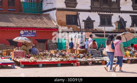 Le persone passeggiano attraverso un mercato con bancarelle piene di prodotti locali, che mostrano il vivace commercio e la tradizione culturale. Foto Stock