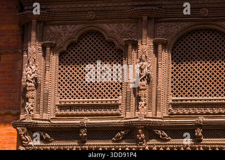 Dettagliate sculture in legno con elementi figurativi che circondano una finestra al Palazzo Hanuman Dhoka. Foto Stock