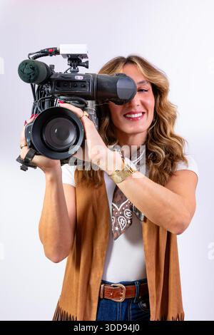 Giovane donna che gestisce una videocamera, concentrata sulla produzione di contenuti multimediali e sulla creazione di contenuti Foto Stock