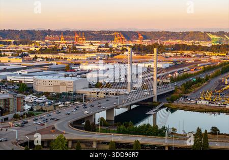 Una splendida vista aerea panoramica cattura l'East 21st Street Bridge con traffico in movimento, illuminato contro un colorato cielo al tramonto sopra Tacoma, Wash Foto Stock
