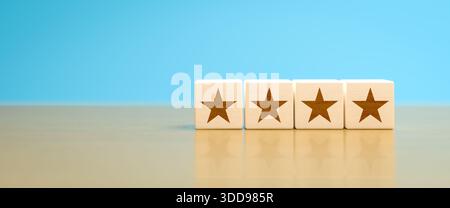 Concetto: Classificazione a 4 stelle. Quattro cubetti di legno con una stella in fila su un tavolo di legno. Messa a fuoco selettiva e Copia spazio Foto Stock