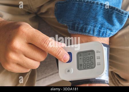 Uomo che controlla la pressione sanguigna con un monitor da polso per la gestione della salute personale Foto Stock