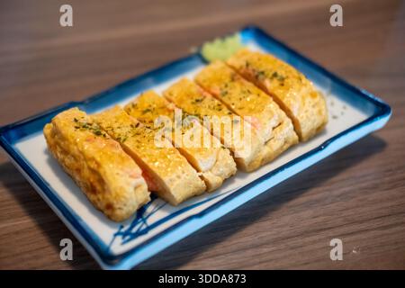 Tamagoyaki, un'omelette giapponese preparata arrotolando diversi strati di uova sbattute fritte, servita su un piatto. Foto Stock