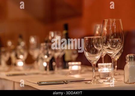 Tavolo da pranzo con bottiglia di vino, bicchieri e piatti, coltello in un'atmosfera calda e accogliente Foto Stock