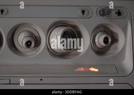 Vista ravvicinata del pannello superiore di un aeromobile con comandi dell'unità di servizio passeggeri per le luci di lettura, le prese d'aria e un pulsante di chiamata. La si accende Foto Stock