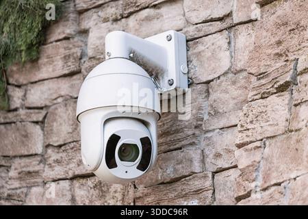 Telecamera di sicurezza montata su un muro di pietra ruvida, che fornisce sorveglianza e mette in risalto la tecnologia di sicurezza e monitoraggio Foto Stock