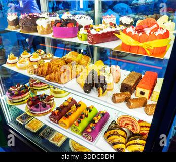 torte diverse con panna e frutta diversa sugli scaffali del negozio Foto Stock