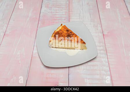 Fetta di cheesecake in stile Philadelphia condita con composta di mirtilli fatta in casa, servita con salsa al caramello e decorata con un gocciolatoio di cioccolato Foto Stock