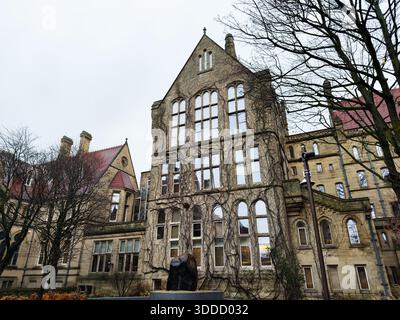 Manchester, Regno Unito - 06 dicembre 2025: Edificio storico di Manchester con edera sulle pareti di pietra e alte finestre ad arco. Foto Stock