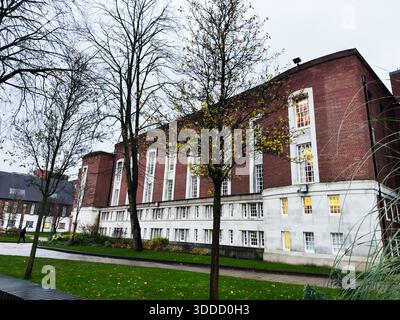 Manchester, Regno Unito - 06 dicembre 2025: Edificio in mattoni con luci calde e alberi nella scena del campus di Manchester. Foto Stock