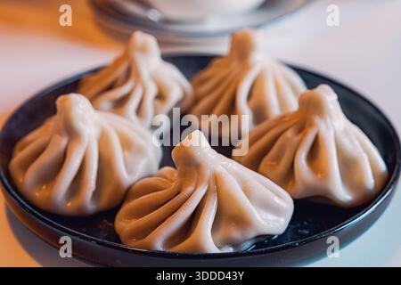 Gnocchi Khinkali serviti su un piatto nero, un piatto tradizionale georgiano popolare per il suo saporito ripieno di carne Foto Stock