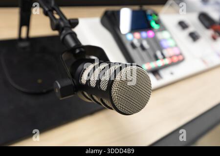 Area di lavoro per la registrazione di podcast con microfono a condensatore professionale su supporto regolabile e mixer audio digitale con comandi illuminati su un design moderno Foto Stock