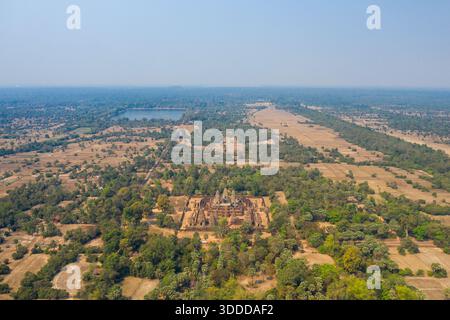 Ampia prospettiva aerea dell'antico complesso del tempio di Pre Rup circondato da campi asciutti, alberi sparsi e bacini d'acqua lontani nella regione di Angkor in Cambogia. La scena cattura la disposizione geometrica del tempio all'interno di un mosaico di campagna rurale sotto cieli azzurri. Foto Stock