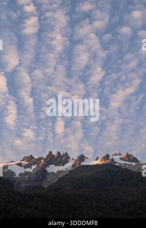 Un primo piano verticale di una spettacolare cresta di montagna con picchi frastagliati e aspri ghiacciai, che brillano di luce calda e dorata all'alba o al tramonto, se Foto Stock