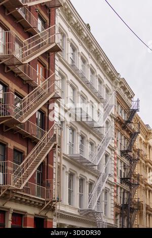 Facciate architettoniche di edifici urbani con vari colori e design, caratterizzate da prominenti fuochi d'incendio contro un cielo pallido. Foto Stock
