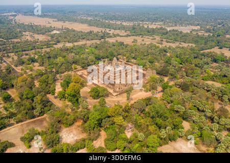 Ampia prospettiva aerea dell'antico complesso del tempio di Pre Rup circondato da campi asciutti, alberi sparsi e bacini d'acqua lontani nella regione di Angkor in Cambogia. La scena cattura la disposizione geometrica del tempio all'interno di un mosaico di campagna rurale sotto cieli azzurri. Foto Stock