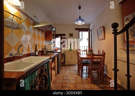Accogliente cucina rustica e zona pranzo con piastrelle gialle e tavolo in legno Foto Stock