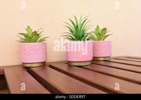tre vasi rosa con fiori verdi artificiali sul tavolo del balcone Foto Stock