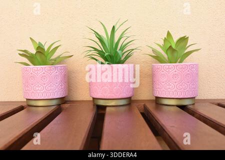 tre vasi rosa con fiori verdi artificiali sul tavolo del balcone Foto Stock