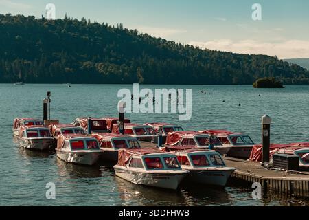 Pedalò ormeggiata sul lago Windermere con pedalatori in lontananza Foto Stock