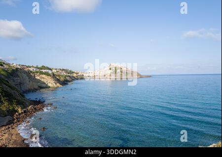 Ampia vista di Castelsardo, arroccata sulla cima di un promontorio roccioso, circondata da acque blu del Mediterraneo e ripide scogliere costiere sotto un cielo limpido in Sardegna. Foto Stock