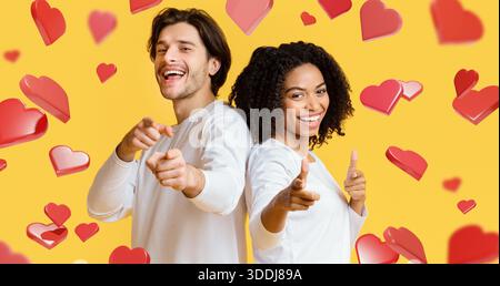 Allegra coppia ride e posa insieme a cuori su sfondo giallo per momenti speciali Foto Stock