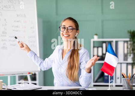Felice insegnante che conduce una coinvolgente lezione online di francese sulle regole base della grammatica Foto Stock