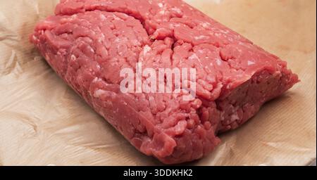 Carne macinata cruda fresca in primo piano su carta pergamena con consistenza dettagliata della carne macinata Foto Stock