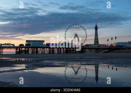 Molo centrale di Blackpool al tramonto con ruota panoramica e Torre di Blackpool riflessa nella sabbia bagnata, Blackpool, Lancashire, Inghilterra, Regno Unito. Foto Stock