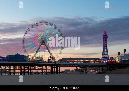 Ruota panoramica in movimento sul molo centrale di Blackpool con Blackpool Tower al tramonto, Blackpool, Lancashire, Inghilterra, Regno Unito. Foto Stock