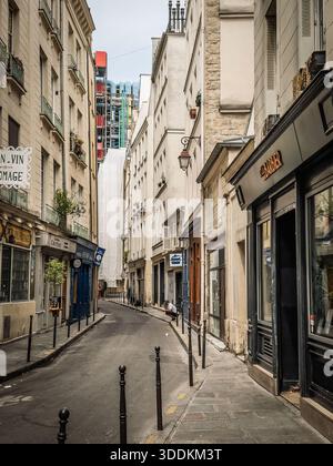PARIGI, FRANCIA - 22 GIUGNO 2025: Una vista su una stretta e vuota strada acciottolata costeggiata da alti edifici storici nel quartiere le Marais di Parigi, i Foto Stock