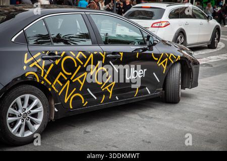 VALENCIA, SPAGNA - 12 APRILE 2025: Un'auto Toyota nera con il logo Uber e il testo di Valencia parcheggiata in una strada cittadina. Uber e' un tecnico di passaggio Foto Stock