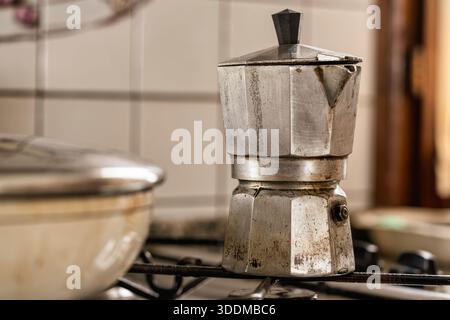 moka rustica su un piano cottura pronto per preparare un caffè espresso forte per un rituale mattutino, luce calda, fascino vintage in alluminio e una casa autentica Foto Stock