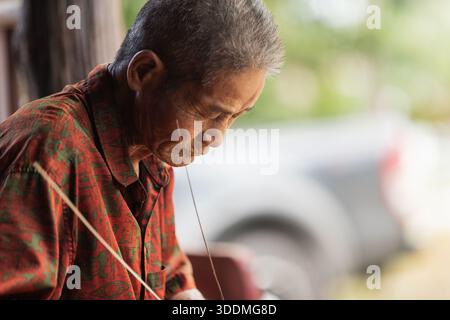 Senior artigiano thailandese che si concentra sulla tradizionale arte della tessitura di bambù Foto Stock