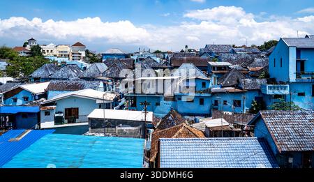 Vista aerea di un'area urbana densamente popolata con case dal tetto blu sotto un cielo parzialmente nuvoloso. Foto Stock
